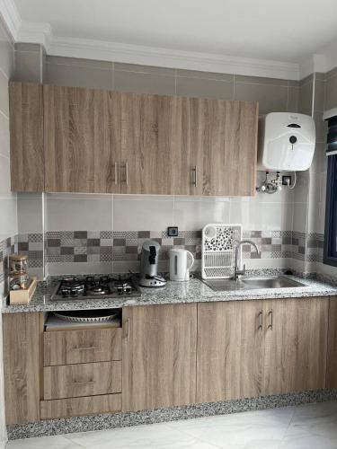 a kitchen with wooden cabinets and a stove top oven at Mini Villa 2 Al hoceima in Al Hoceïma
