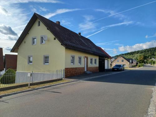 a white house with a black roof on a street at Ferienhaus in der Nähe der Skipiste in Stadlern