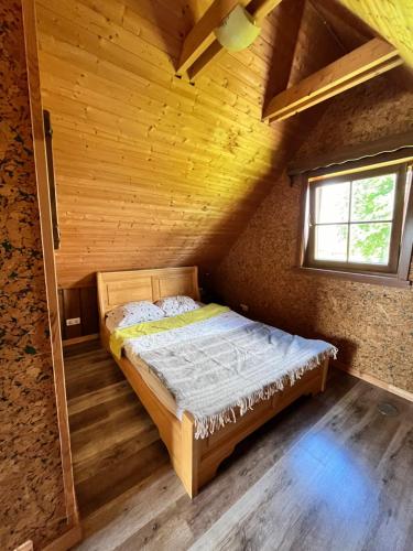 a bed in a wooden room with a window at Milžinai Retreat in Zarasai