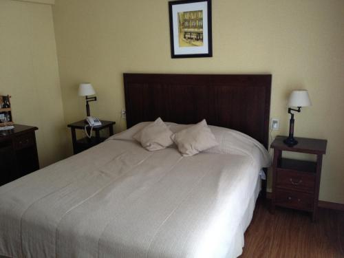 a bedroom with a large white bed with two night stands at Hotel Europa in Montevideo