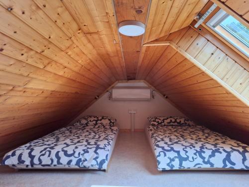 two beds in a room with a wooden ceiling at Apartma Pod orehom in Slap ob Idrijci