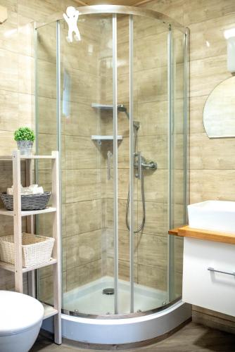 a shower with a glass door in a bathroom at Domki Pod Lasem Lubkowo in Lubkowo