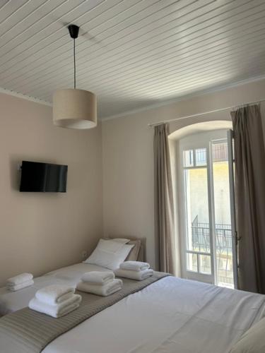 a white bedroom with a bed with towels on it at Arco Boutique Apartments in Paralio Astros