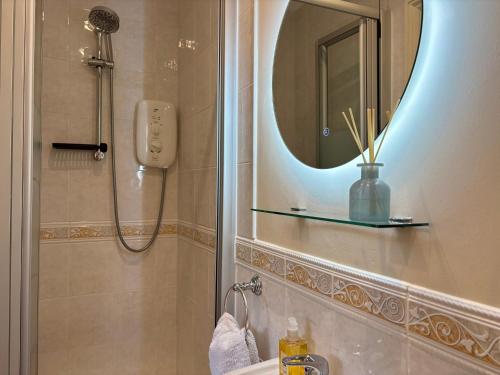 a bathroom with a shower with a mirror and a sink at Seagulls Rest - Sheringham in Sheringham