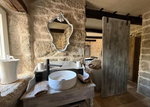 a stone bathroom with a sink and a mirror at Le Petit Refuge - La Petite Longère in Rahon