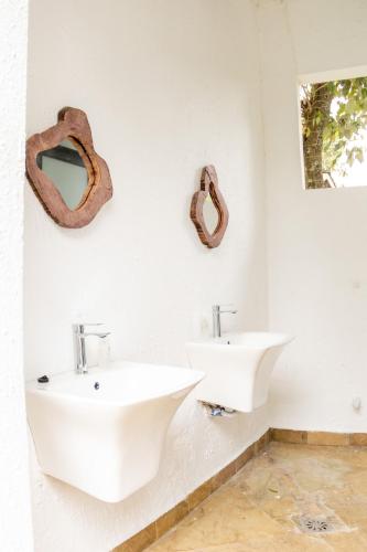 a bathroom with two sinks and two mirrors on the wall at Olarashii River Lodge in Arusha