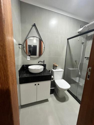a bathroom with a sink and a toilet and a mirror at Casa 3 Quartos Recanto Buritis in Santa Teresa