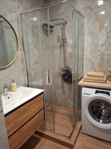 a bathroom with a shower and a washing machine at Atokvėpis sielai in Šilutė