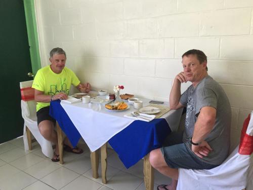 two men sitting at a table with food on it at Moatoga Hotel in Apia