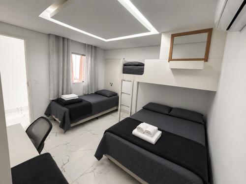 a small room with two beds and a chair at Aconchego de Lugar - Eri & Douglas - 4 in Belo Horizonte