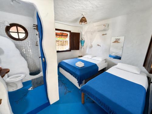 a small room with two beds and a shower at Pousada Cavallitos d'Amar in Ilha de Boipeba
