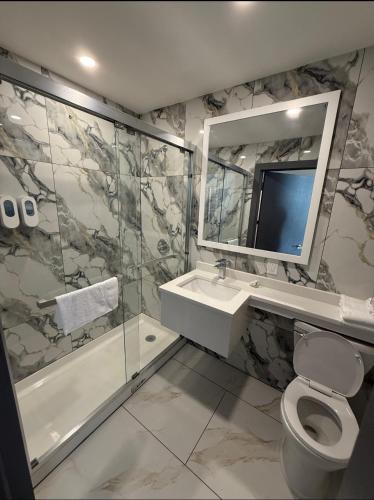 a bathroom with a toilet and a sink and a shower at Skylux Hotel - Long Island City in Queens