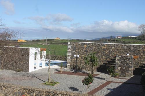 a stone wall with a swimming pool next to a building at Quinta das Giestas in Ribeira Grande