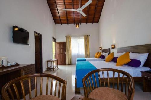 a bedroom with a bed with blue and yellow pillows at Okwin Resort Nawalapitiya in Kandy
