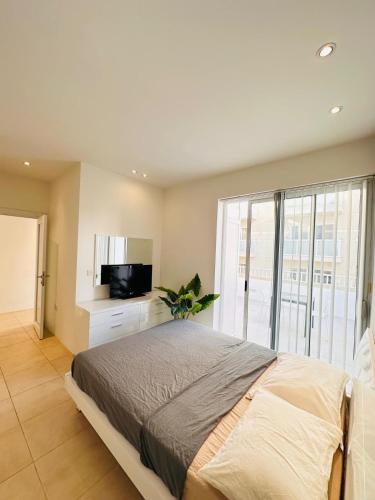 a bedroom with a large bed and a television at Maltese House Gzira Central in Il-Gżira