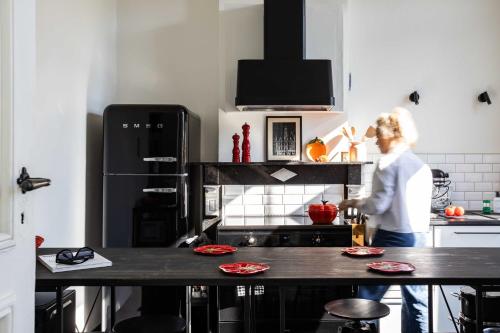 a woman standing in a kitchen with a counter at Historisch herenhuis voor 12 personen met volledig ommuurde tuin in Oudenaarde