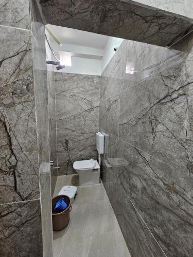 a bathroom with a toilet and a stone wall at Siyara Hotel in Khamaria