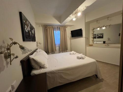 a bedroom with a bed with white sheets and a window at Psichro Apartments Hera in Magoulás