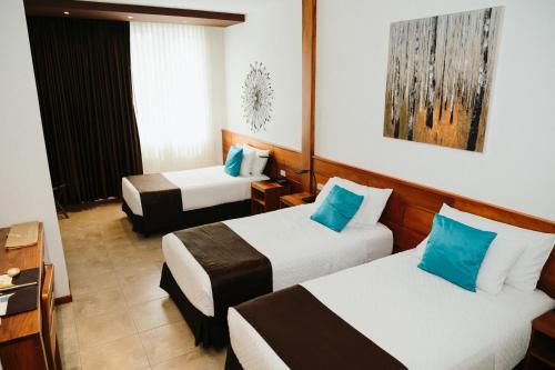 a hotel room with two beds with blue pillows at Hotel Cucuve in Puerto Ayora