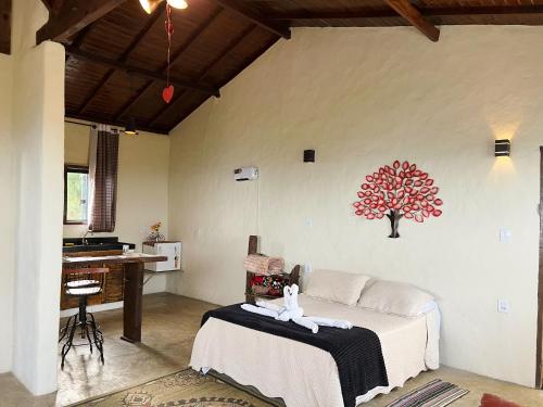a room with a bed and a table with a tree on the wall at Chalés do Chá in Lavras Novas