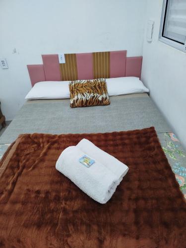 a room with two beds and a towel on a rug at Minha casa pousada in Botucatu