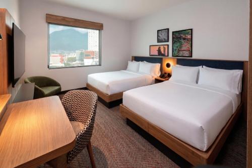 a hotel room with two beds and a table at Hampton by Hilton Monterrey Tecnológico in Monterrey