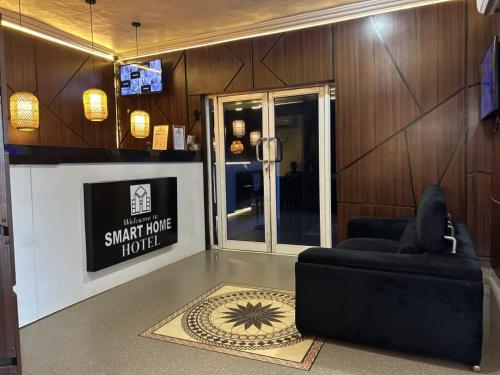 a living room with a black couch and a tv at Smarthome Hotel in Benin City