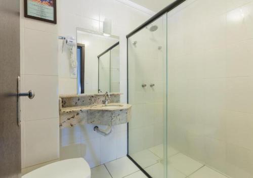 a bathroom with a glass shower and a sink at Rede Andrade Royal Criciúma in Criciúma