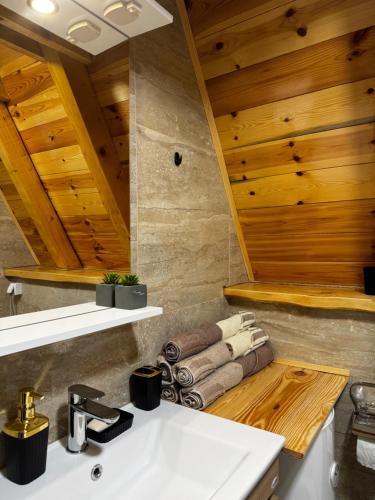 a bathroom with a white sink and wooden ceilings at Villa Komarnica Hideaway in Šavnik