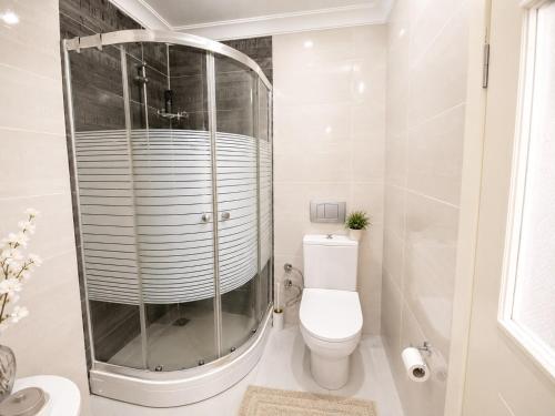 a white bathroom with a shower and a toilet at Ada Hill Ayvalık in Ayvalık