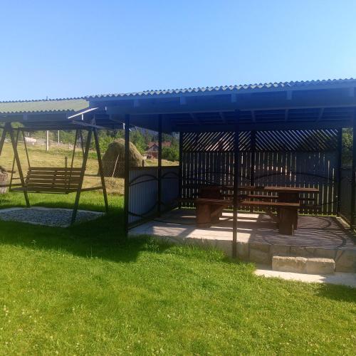 a picnic shelter with two benches in a park at Оксана та Назар in Mykulychyn