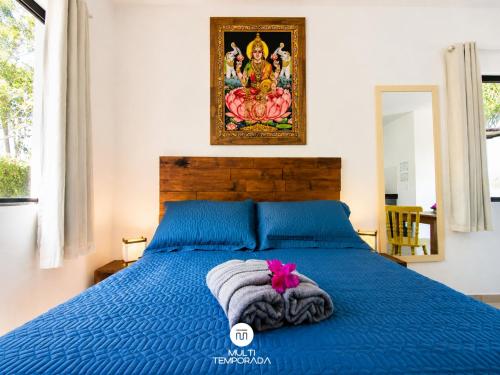 a bedroom with a blue bed with a towel on it at Lugar ao Sol - Flats c/ Cozinha no Rosa in Praia do Rosa