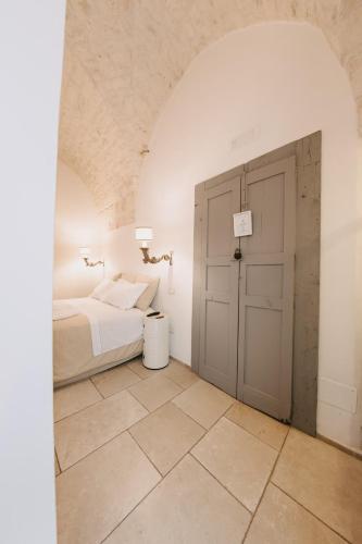 a white bedroom with a bed and a door at Nobile Dimora di Puglia in Ostuni