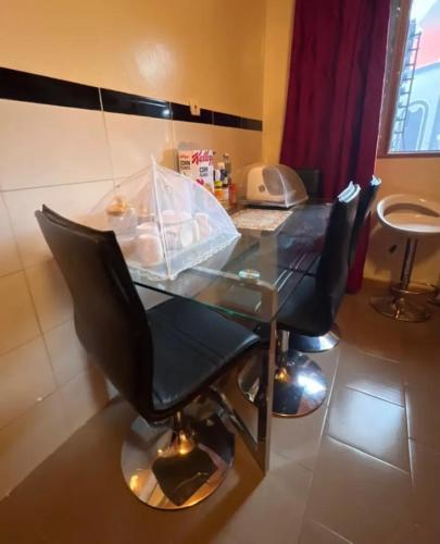 a glass table with two chairs and a telephone at Spacious Apartment with Pool in M'bour - 100 m² in Mbour