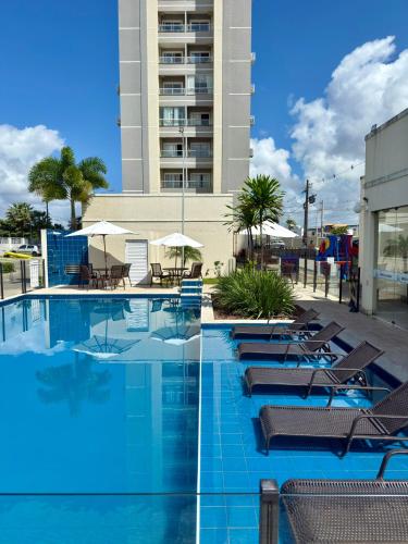 a swimming pool with chairs and umbrellas and a building at Auréa Residência - a 500 m da Praia in Cabedelo