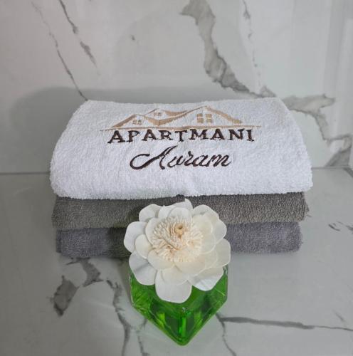 a pile of towels with a white flower in a vase at Apartmаn Avram ll in Kotor-Varoš