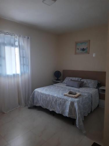 a bedroom with a bed with a blue blanket and a window at Machado Monteiro in Guarapari