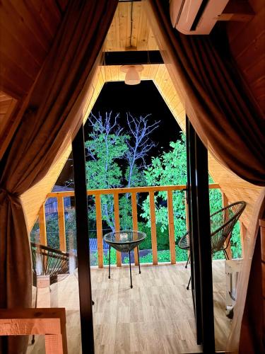 a view of a screened in porch with a table on a deck at ჰარმონია Harmony Cottage in Ambrolauri