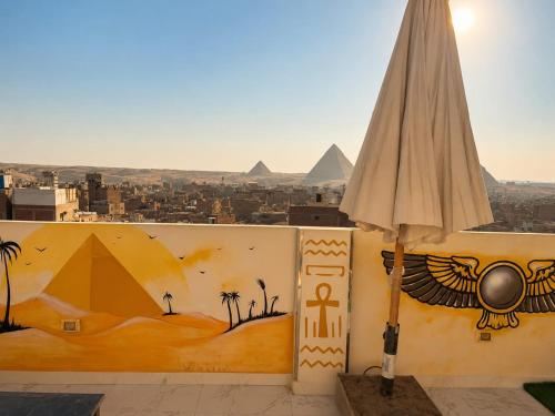 an umbrella next to a wall with a view of pyramids at Pyramids View Rooftop Apartment in Ghaţāţī