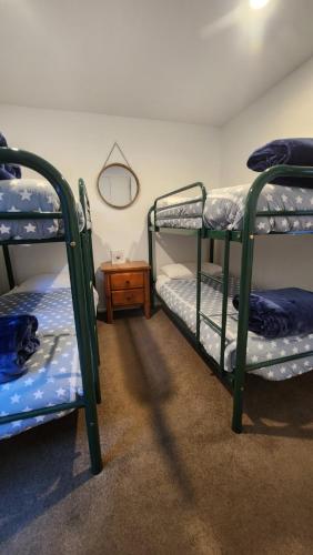 a room with three bunk beds and a table at Luxury on Lakeside in Wanaka