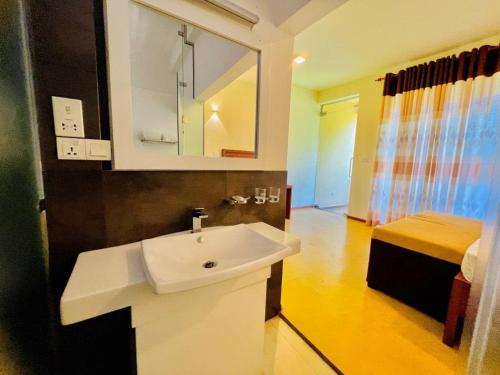 a bathroom with a white sink and a bed at Villa Rustic in Negombo