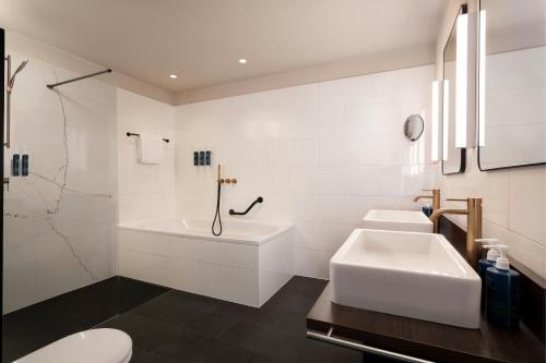 a white bathroom with two sinks and a tub at Four Points Sheraton Bolzano Bozen in Bolzano