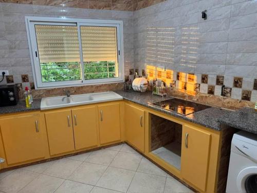 a kitchen with yellow cabinets and a sink and a window at un nouveau appartement avec un parking sur place in Tunis