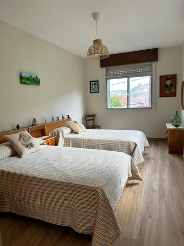 a bedroom with three beds and a window at Casiña Carreiro in Beade