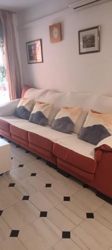 a couch in a living room with pillows on it at apartamento cerca playa ,estación tren y garaje gratis in Segur de Calafell