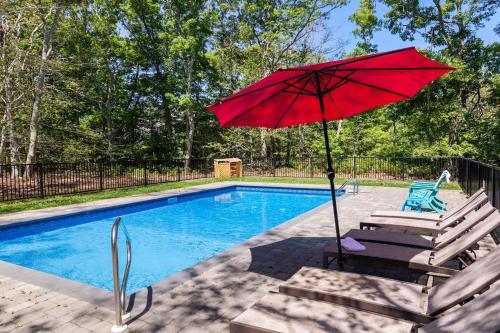 a red umbrella sitting next to a swimming pool at Spacious Home with Private In-Ground Pool in Brewster