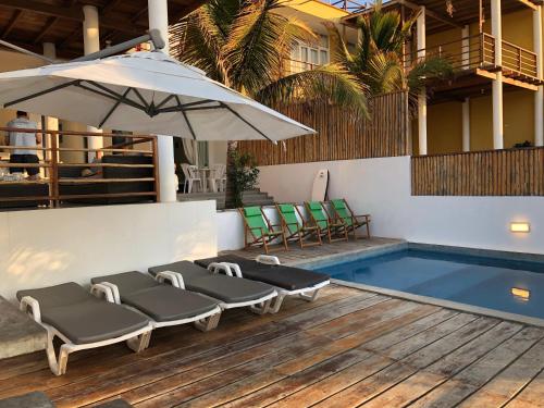 a pool with four lounge chairs and an umbrella at Villa Vichayito Relax in Vichayito