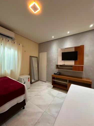 a bedroom with a bed and a flat screen tv at Pousada Mineira in Barreirinhas