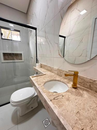 a bathroom with a sink and a toilet and a mirror at Pousada Mineira in Barreirinhas