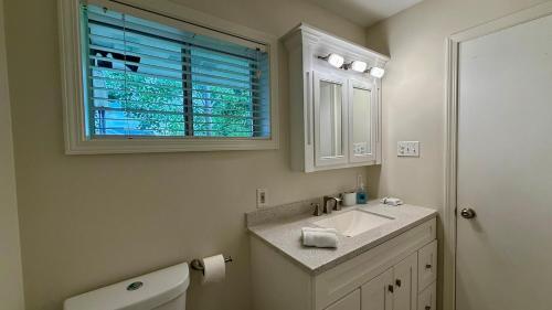 a bathroom with a toilet and a sink and a window at Sabana in Lake Charles